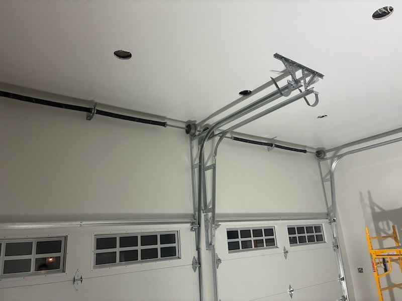 Smooth light-colored garage walls and ceiling around overhead door tracks in the Northbridge project.