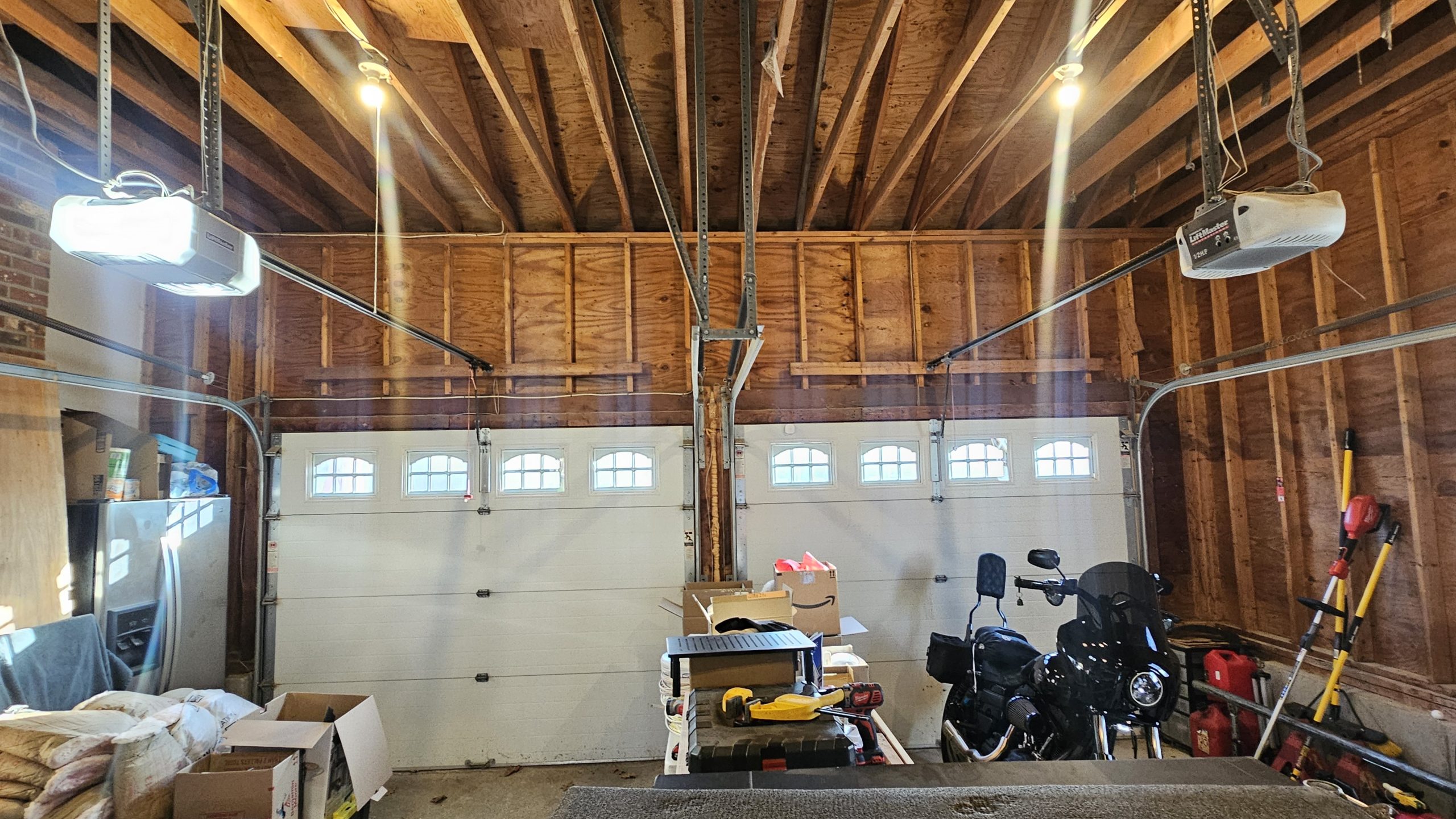 Exposed wall and ceiling framing above two garage doors in a Northbridge garage before drywall installation.