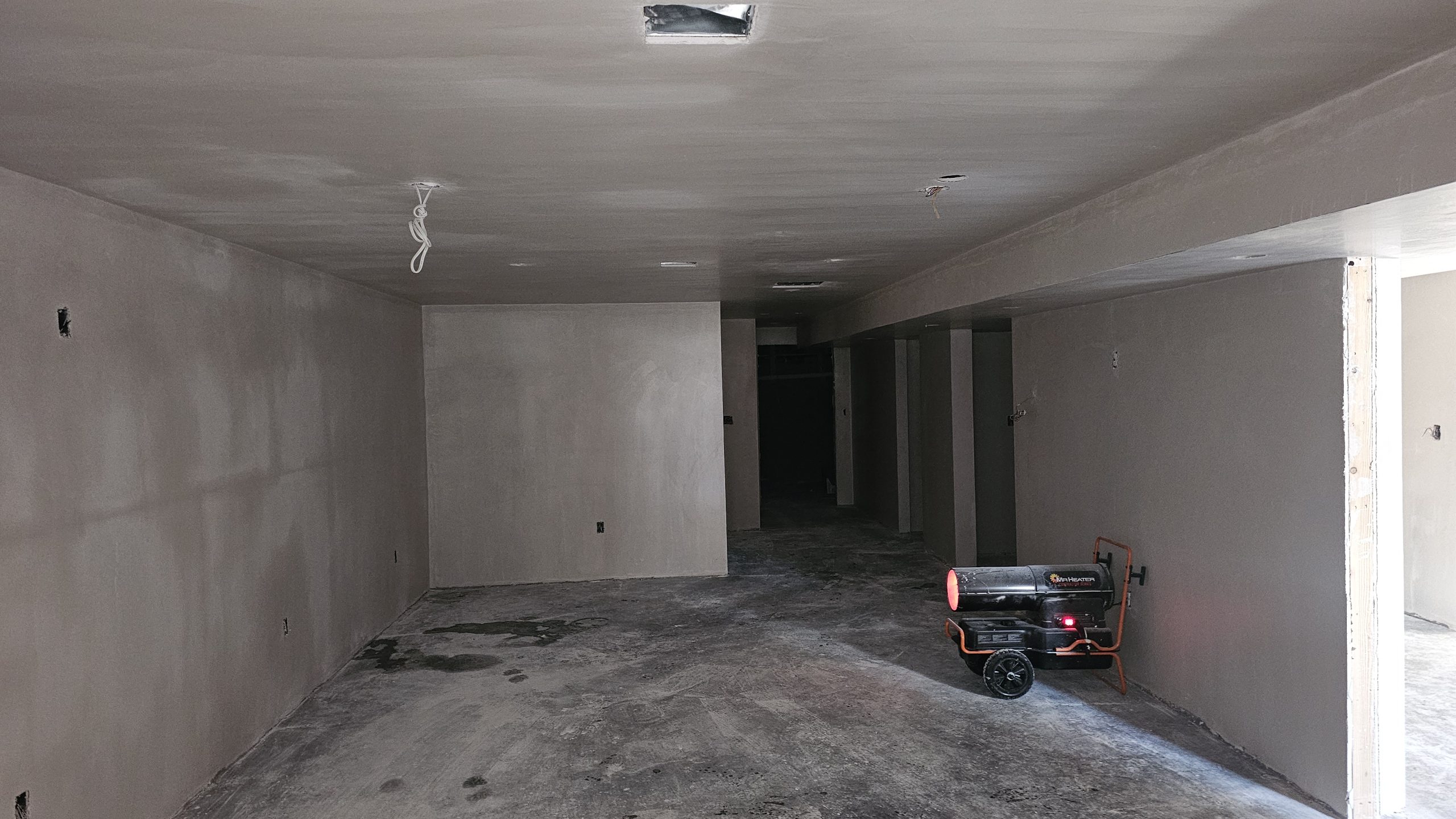 Plaster-finished walls and ceiling in a Worcester basement, with unfinished floor and fixture openings.