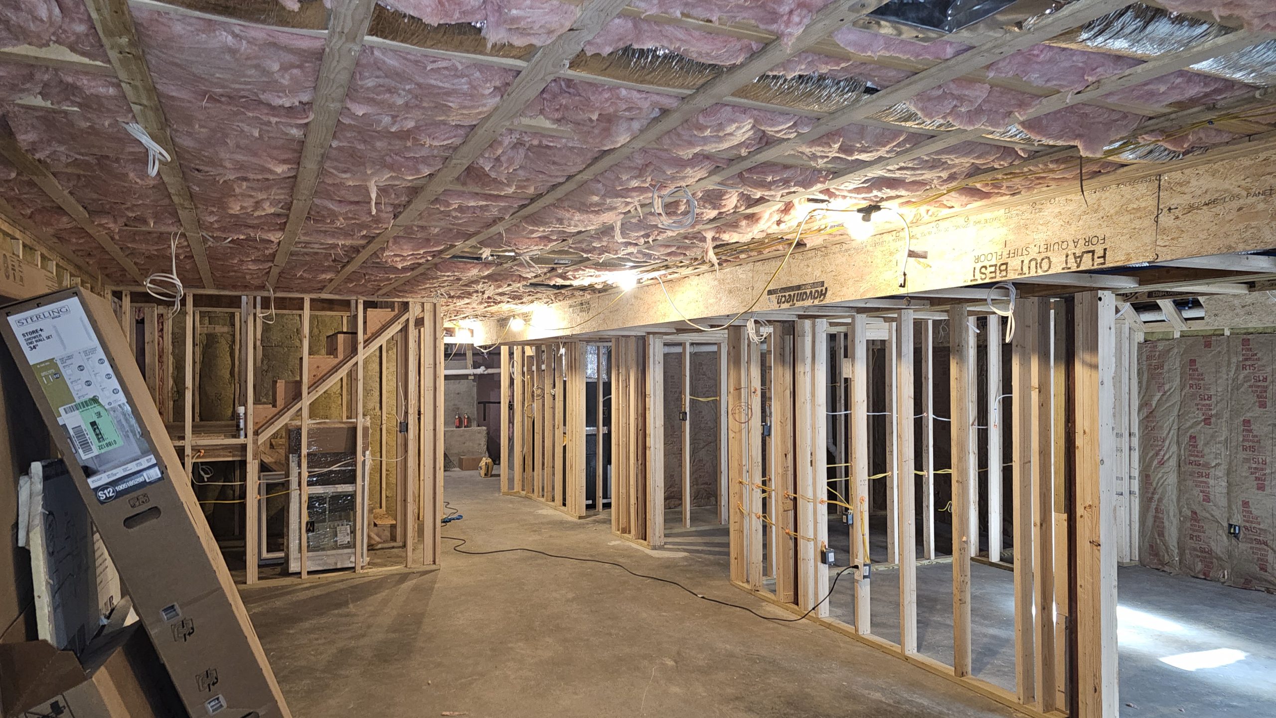 Exposed wall framing and insulated ceiling framing before drywall installation in a Worcester basement.