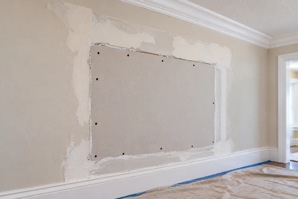 New drywall installed in a controlled repair area beside existing drywall